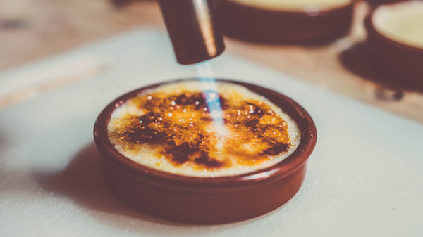 Chalumeau à crème brûlée caramélisant le sucre avec une flamme jet